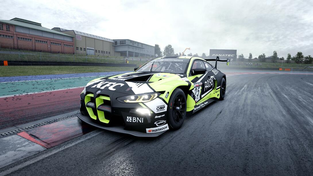 BMW M4 GT3 going over a kerb in the wet, with a WRT Dubai 24H livery